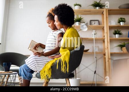 Kleines Mädchen, das Buch mit Mutter zu Hause liest Stockfoto