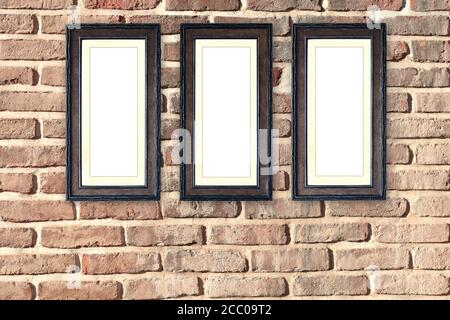 Drei alte hölzerne leere Bilderrahmen auf alten Ziegelwänden. Leerer Retro-Rahmen an der Zimmerwand. Mustervorlage. Platz für Text kopieren Stockfoto