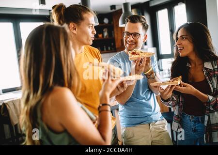 Fröhliche multirassische Freunde, die Spaß haben und Pizza zu Hause essen Stockfoto