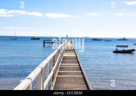 One point perspective view toward the sea with ships sailing and wooden bridge in the middle during the summer period. Stockfoto