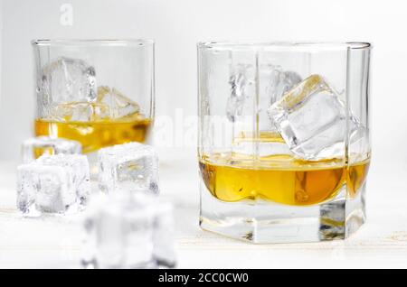 Zwei Gläser Scotch Whiskey mit Eiswürfeln, weißer Hintergrund, Holzhintergrund Stockfoto
