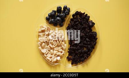 Beeren und Nüsse in runden Kunststoffbehälter für die Lagerung von Lebensmitteln - gelber Hintergrund Stockfoto
