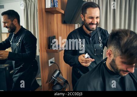 Positive begeistert jungen Mann macht stilvolle Frisur Stockfoto