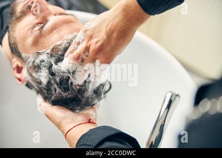 Fokussierte Foto auf männliche Hand, die Haare waschen Stockfoto