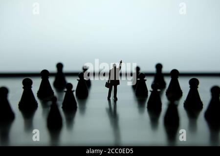 Business-Strategie Konzeptfoto - Silhouette der Miniatur des Geschäftsmannes Mit dem Kopf in der Mitte des Schachspiels auf einem Schachbrett Stockfoto