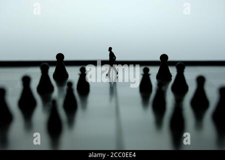 Business-Strategie konzeptuelles Foto - Miniatur des Geschäftsmannes, der vorwärts geht In der Mitte des Schachspiels auf einem Schachbrett Stockfoto