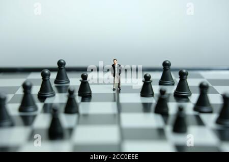 Business-Strategie konzeptuelles Foto - Miniatur des Geschäftsmannes, der vorwärts geht In der Mitte des Schachspiels auf einem Schachbrett Stockfoto