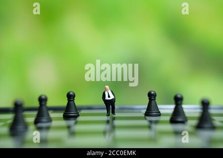Business-Strategie konzeptuelles Foto - Miniatur des Geschäftsmannes stehend in Die Mitte des Schachspiels auf einem Schachbrett Stockfoto