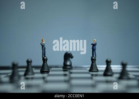 Business-Strategie konzeptuelles Foto - Miniatur Geschäftsmann über Schloss stehen Bauer auf einem Schachbrett Stockfoto