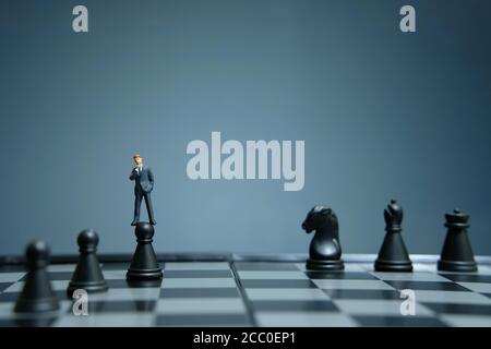 Business-Strategie konzeptuelles Foto - Miniatur Geschäftsmann über Schloss stehen Bauer auf einem Schachbrett Stockfoto