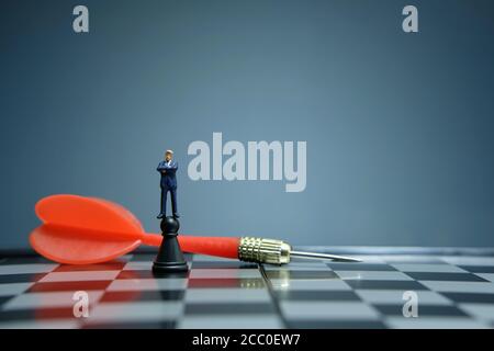 Business-Strategie konzeptuelles Foto - Miniatur Geschäftsmann über Schloss stehen Bauer auf einem Schachbrett mit rotem Pfeil Stockfoto