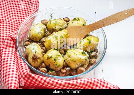 Gebratene junge Kartoffeln in Glasbackform mit Pilzen. Stockfoto