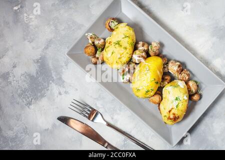 Gebratene junge Kartoffeln auf dem Teller mit Pilzen. Draufsicht, Stockfoto