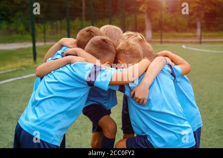 Kinder Fußballmannschaft umarmen einander auf Fußballplatz vor Übereinstimmung Stockfoto