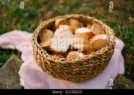 Eine Nahaufnahme eines Korbkorbes, gefüllt mit Scheiben frisches Brot auf einer rosa Stoffmatte. Stockfoto