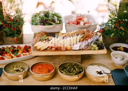 Tiefe Platte mit Vorspeisen auf dem Tisch mit Schneidebrett mit Aufschnitt und Käse und Caprese und Salat Tabletts. Stockfoto