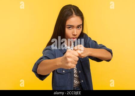 Lasst uns kämpfen! Portrait von selbstbewussten mutigen Mädchen in Denim-Shirt halten Fäuste geballt, Boxen und Stanzen bei der Kamera, ihr Blick Ausdruck Wut Fell Stockfoto