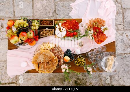 Draufsicht auf einen Tisch mit Köstlichkeiten für die Feier und leeren Gläsern für Champagner. Stockfoto