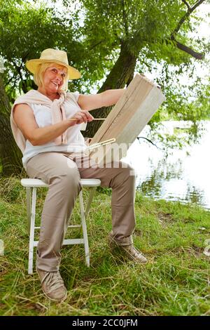 Frau mit Staffelei beim Malen eines Bildes in der Natur Stockfoto