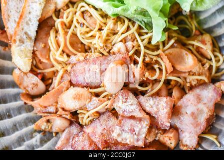 Gebratene Spaghetti mit Wurst Schinken Gemüse und Käse auf dem Teller, Draufsicht Stockfoto