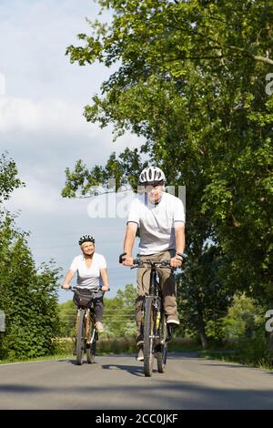Frau und Mann fahren im Sommer Fahrräder mit Helmen Stockfoto