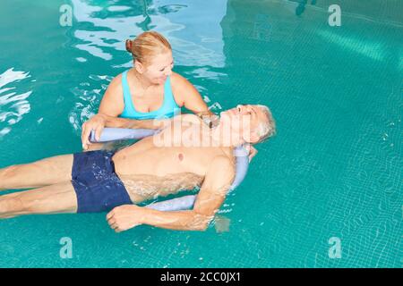 Senior Mann bekommt Hydrotherapie im Schwimmbad von einem Physiotherapeut Stockfoto