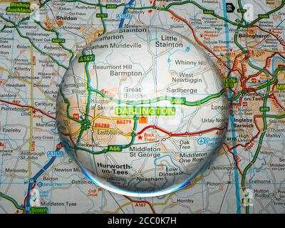 Nahaufnahme einer kuppelförmigen Lupe über einer Seite einer britischen Straßenatlas-Karte, mit der Darlington-Gegend von England vergrößert für eine genauere Ansicht. Stockfoto