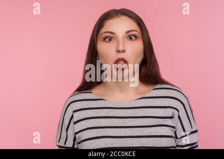 Portrait einer lustigen dummen amüsanten Frau im gestreiften Sweatshirt, die mit gekreuzten Augen steht, die Zunge zeigt und einen dummen, hirnlosen Gesichtsausdruck macht Stockfoto