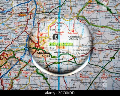 Nahaufnahme einer kuppelförmigen Lupe über einer Seite einer britischen Straßenatlas-Karte, mit der Cheltenham-Gegend von England vergrößert für eine genauere Ansicht. Stockfoto
