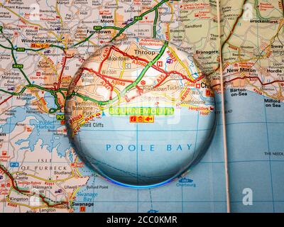 Nahaufnahme einer kuppelförmigen Lupe über einer Seite einer britischen Straßenatlas-Karte, mit der Bournemouth-Region von England vergrößert für eine genauere Ansicht. Stockfoto