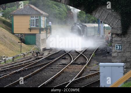 Eine U-Lokomotive, die einen Dampfzug unter einer Straßenbrücke zieht. Stockfoto