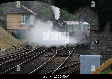 Eine U-Lokomotive, die einen Dampfzug unter einer Straßenbrücke zieht. Stockfoto