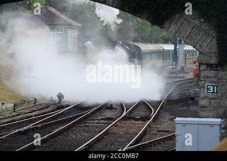 Eine U-Lokomotive, die einen Dampfzug unter einer Straßenbrücke zieht. Stockfoto