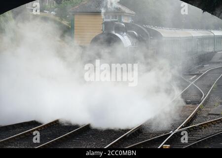 Eine U-Lokomotive, die einen Dampfzug unter einer Straßenbrücke zieht. Stockfoto