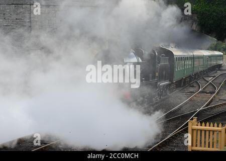 Eine U-Lokomotive, die einen Dampfzug unter einer Straßenbrücke zieht. Stockfoto