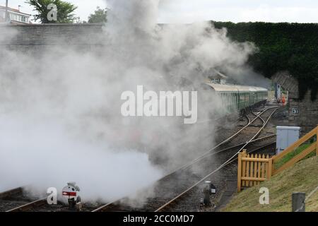 Eine U-Lokomotive, die einen Dampfzug unter einer Straßenbrücke zieht. Stockfoto