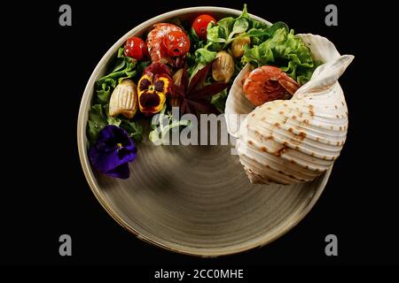 Gegrillte Garnelen und Gemüsesalat auf schwarzem Teller Stockfoto