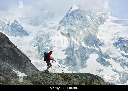 Waagerechte Momentaufnahme des erstaunlichen, felsigen Ober Gabelhorn im Schnee in den Pennine Alpen in der Schweiz, zwischen Zermatt und Zinal gelegen, Wanderwanderungen mit Wanderstöcken im Vordergrund Stockfoto