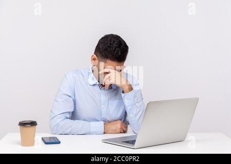 Verärgert Mann Mitarbeiter sitzen Büroarbeitsplatz mit Laptop auf dem Schreibtisch, verbeugen Kopf und weinen, Gefühl deprimiert, besorgt über Probleme bei der Arbeit, verloren Job. Stockfoto