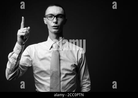 Junger hübscher androgyner Geschäftsmann vor grauem Hintergrund Stockfoto