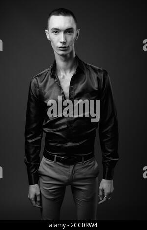 Junger hübscher androgyner Geschäftsmann vor grauem Hintergrund Stockfoto