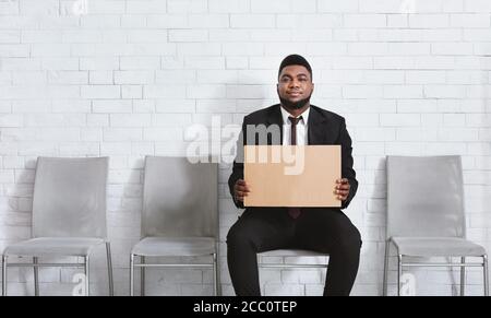 Serious schwarzen Mann im Büro tragen leere Zeichen in der Firmenhalle halten, warten auf Vorstellungsgespräch. Speicherplatz kopieren Stockfoto