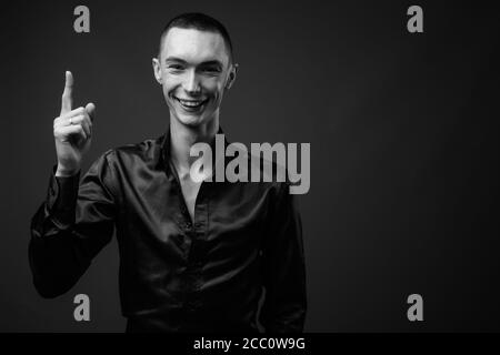 Junger hübscher androgyner Geschäftsmann vor grauem Hintergrund Stockfoto