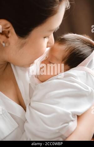 Nahaufnahme einer jungen Frau, die ein neugeborenes Baby in den Armen hält. Stockfoto