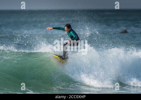 Ein junger Teenager surft auf dem Kamm einer Welle am Fistral in Newquay in Cornwall. Stockfoto