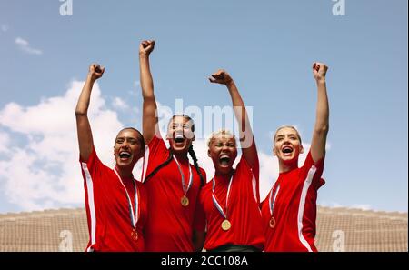 Professionelle Fußballspielerinnen feiern einen Sieg in einer Sportarena. Gruppe von Fußballspielerinnen schreien und Punch Luft nach dem Gewinn der Stockfoto