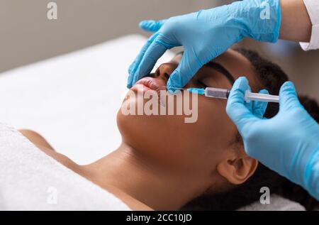 Schwarze Dame bekommen Lippe Füllung Injektion im Schönheitssalon Stockfoto