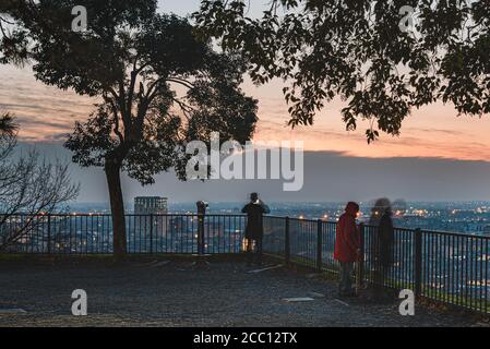 Verschwommen wie Menschen genießen Sie die Skyline der Stadt von einem beliebten Balkon auf Colle Cidneo auf der Piazza del Castello bei Sonnenuntergang. Melancholische Atmosphäre, Brescia Stockfoto