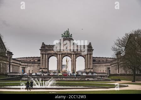 An einem düsteren Wintertag machen die Leute ein Foto mit den beliebten Arcades du Cinquantenaire. Grimmiger Tag im Park des 50. Jahrestages - Brüssel Stockfoto