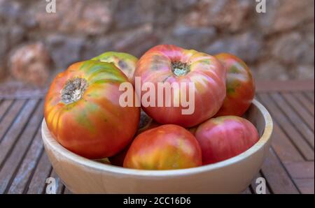 Eine Schüssel voll mit frischen Moruno Tomaten in einem hölzernen Hintergrund Stockfoto